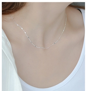 Close-up of minimalist S925 sterling silver chain with shimmering discs on collarbone