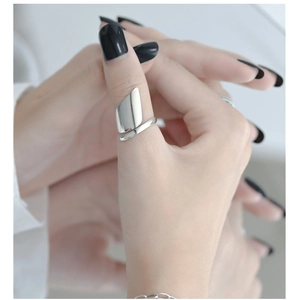 Detailed view of irregular polished silver geometric ring worn on thumb as a bold statement
