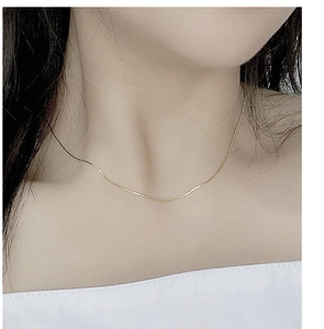 Detail of a delicate gold S925 sterling silver thin chain necklace on a female collarbone