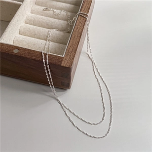Double-layer S925 sterling silver water wave chain necklace on a wooden jewelry box