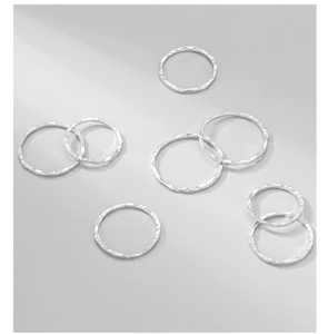 Macro detail of slim S925 sterling silver rings with hand-hammered texture and reflective finish