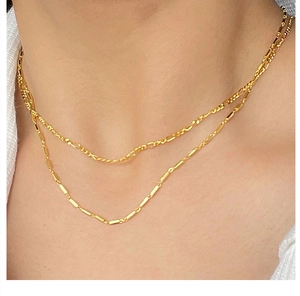 Close-up of layered S925 sterling silver Figaro and link chain necklaces in gold