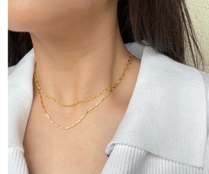Close-up of a double-layered gold Figaro and bamboo chain necklace worn on a neck