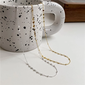 Detail of S925 sterling silver necklaces with tiny heart and bead charms on ceramic cup