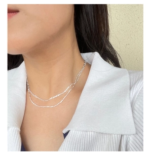 Close-up of layered S925 sterling silver Figaro chain necklace on female model
