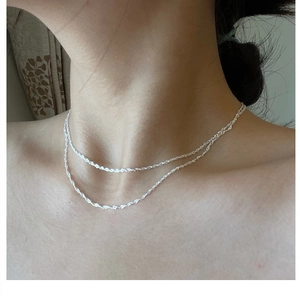 Close-up of double layer silver water wave chain necklace worn on neck by a model