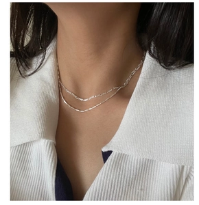 Close-up of double layer S925 sterling silver Figaro chain necklace worn by a model