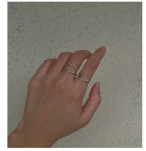Détail d'une bague courbée en argent S925 et d'un anneau triple vague sur les doigts