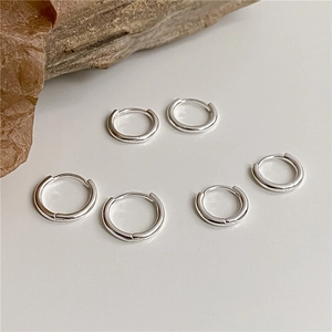 Three pairs of S925 sterling silver hoop earrings in varying sizes on a minimalist stone