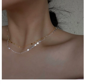 Detail of layered S925 sterling silver clover necklaces on model for a stylish look