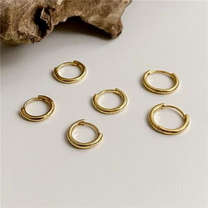 Detailed view of three pairs of classic polished gold hoop earrings on white surface