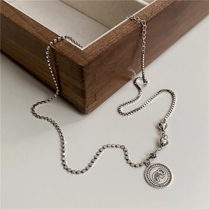 Detail of vintage silver elephant coin pendant with heart accents on mixed chain necklace