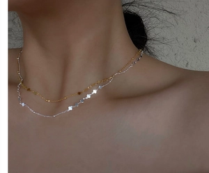 Detail of layered S925 sterling silver necklaces with tiny clover charms on a model