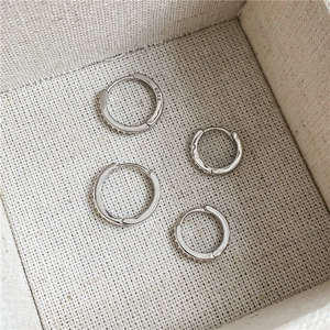 Détail de boucles d'oreilles huggies en argent S925 et zircons dans une boîte à bijoux