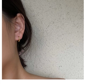 Close-up of minimalist golden S925 sterling silver hoop earring worn on an earlobe