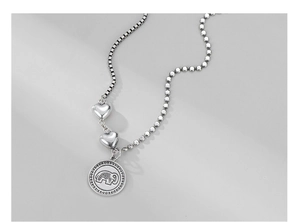 Close-up of retro S925 silver necklace with elephant coin and heart pendants detail