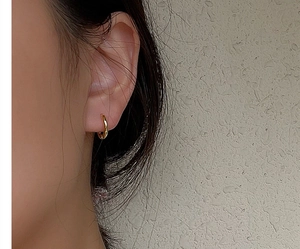 Close-up of minimalist gold S925 sterling silver huggie earring on model ear