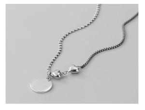 Detailed view of S925 silver necklace with round tag and double heart pendants