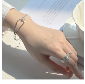 S925 silver knot bracelet and textured wide ring worn for a minimalist elegant style