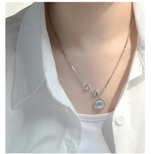 Close-up of S925 sterling silver necklace with elephant coin and heart pendants on model