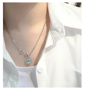 Close-up of S925 sterling silver necklace featuring elephant coin and heart pendants