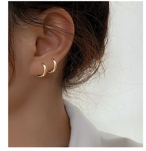 Close-up of classic gold S925 sterling silver hoop earrings worn on a model's ear