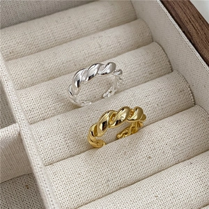 Polished S925 sterling silver twist rings in gold and silver finishes on linen background