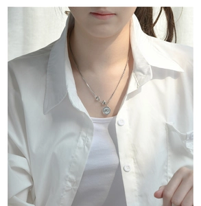 Detail of S925 sterling silver elephant coin necklace with small heart charms on model