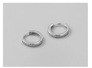 Détail de boucles d'oreilles huggie en argent 925 avec une rangée de zircons incrustés