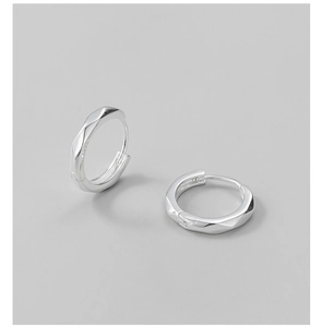 Macro detail of S925 sterling silver hoop earrings with geometric faceted texture and hallmark