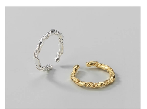Detail of twisted silver and gold rings with polished texture and adjustable open bands