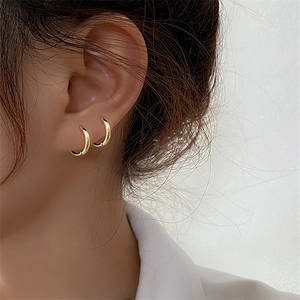 Minimalist S925 sterling silver gold hoop earrings shown layered on a female model's ear