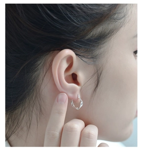 Vue latérale macro d'un modèle portant des boucles d'oreilles créoles torsadées en argent S925
