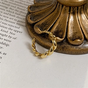 Detailed view of gold twisted croissant ring resting against vintage metal prop on magazine