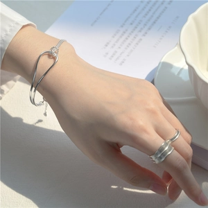 Minimalist S925 sterling silver knot bracelet and textured wide ring worn on model hand
