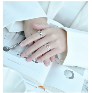 Detailed shot of braided and hollow silver ring worn with a white suit jacket