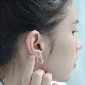Boucle d'oreille créole minimaliste en argent S925 au design torsadé portée par un mannequin