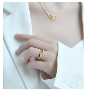 Detailed close-up of golden croissant ring styled with a matching necklace on a model