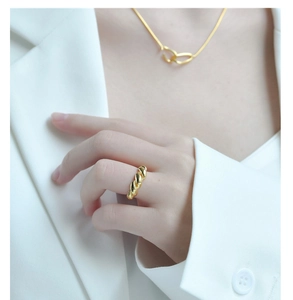 Close-up of minimalist gold croissant dome ring on finger with matching necklace