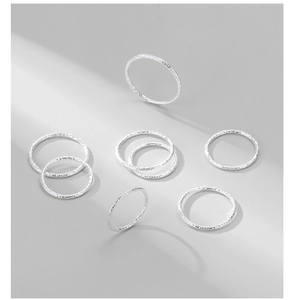 Close-up of 8-piece silver stacked rings set with hammered texture and matte finish