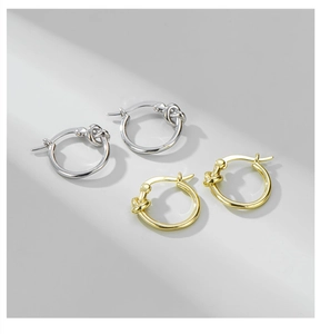 Detail of twisted knot hoop earrings in polished gold and silver finishes on grey background
