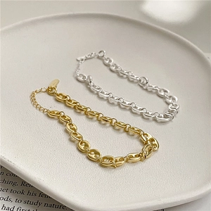 Detail view of gold and silver S925 sterling silver pig nose chain bracelets on ceramic