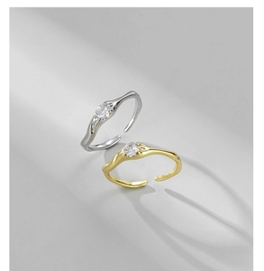 Dettaglio di anelli regolabili in argento e oro con trama lavica e pietre di zircone