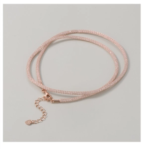 Macro detail of rose gold mesh necklace with sparkling crystals and heart charm clasp