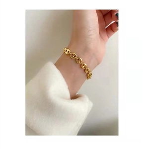 Close-up of golden pig-nose chain bracelet worn on wrist with white plush sleeve cuff