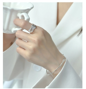 Gros plan d'une bague S925 en argent sterling à texture lave et d'un bracelet élégant au poignet