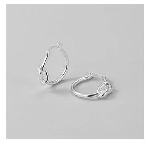 Détail macro de boucles d'oreilles créoles en argent S925 avec nœud élégant