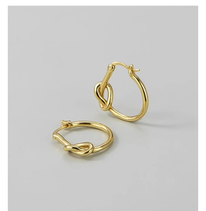 Détail macro de boucles d'oreilles nœud plaquées or montrant la texture du métal