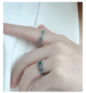 Close-up of vintage 925 silver stacked rings with black heart stone and woven texture