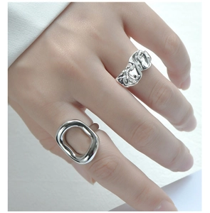 Detail of silver rings featuring irregular lava texture and geometric hollow design